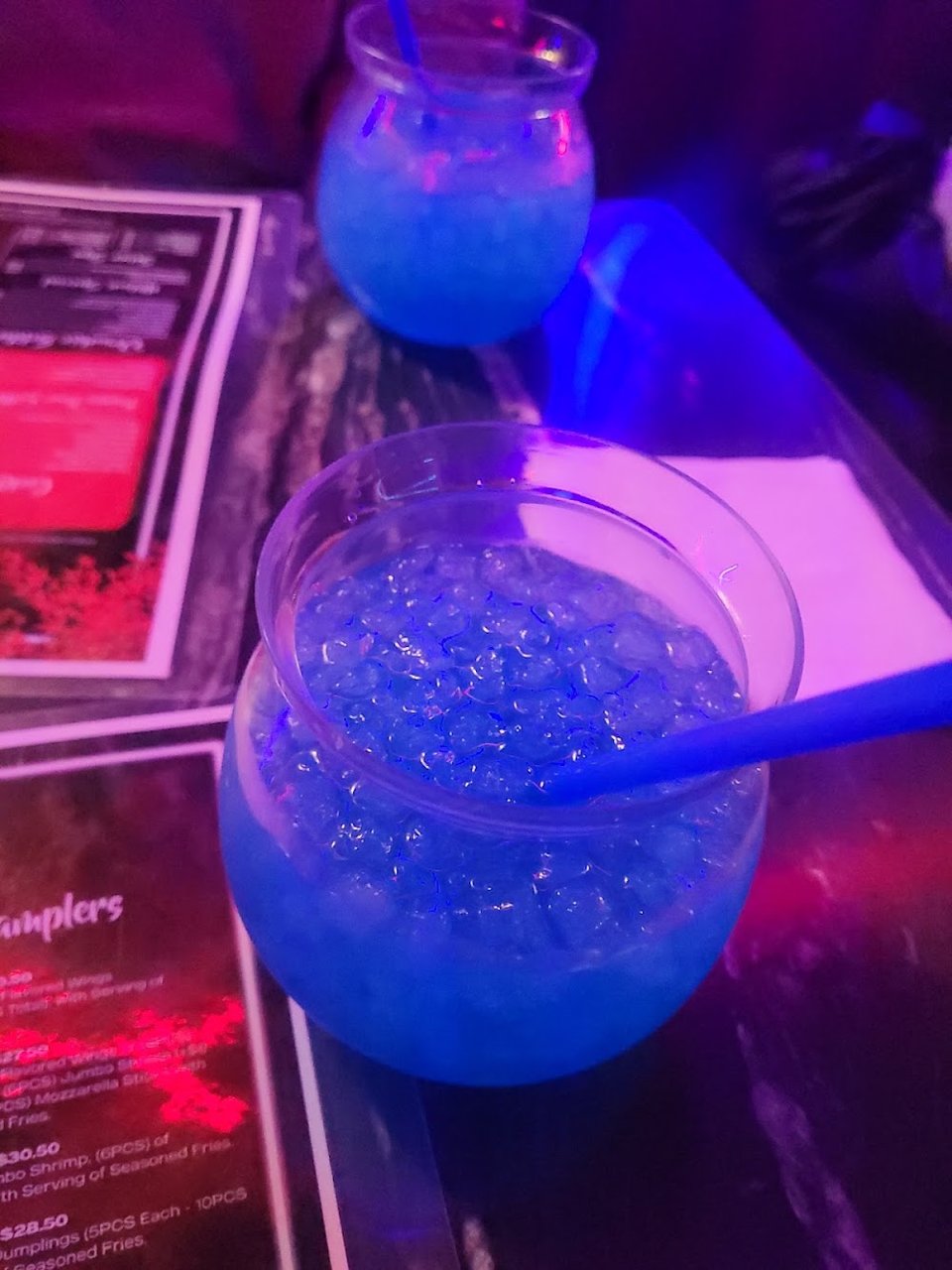 Cocktail menu beside a dimly lit table.