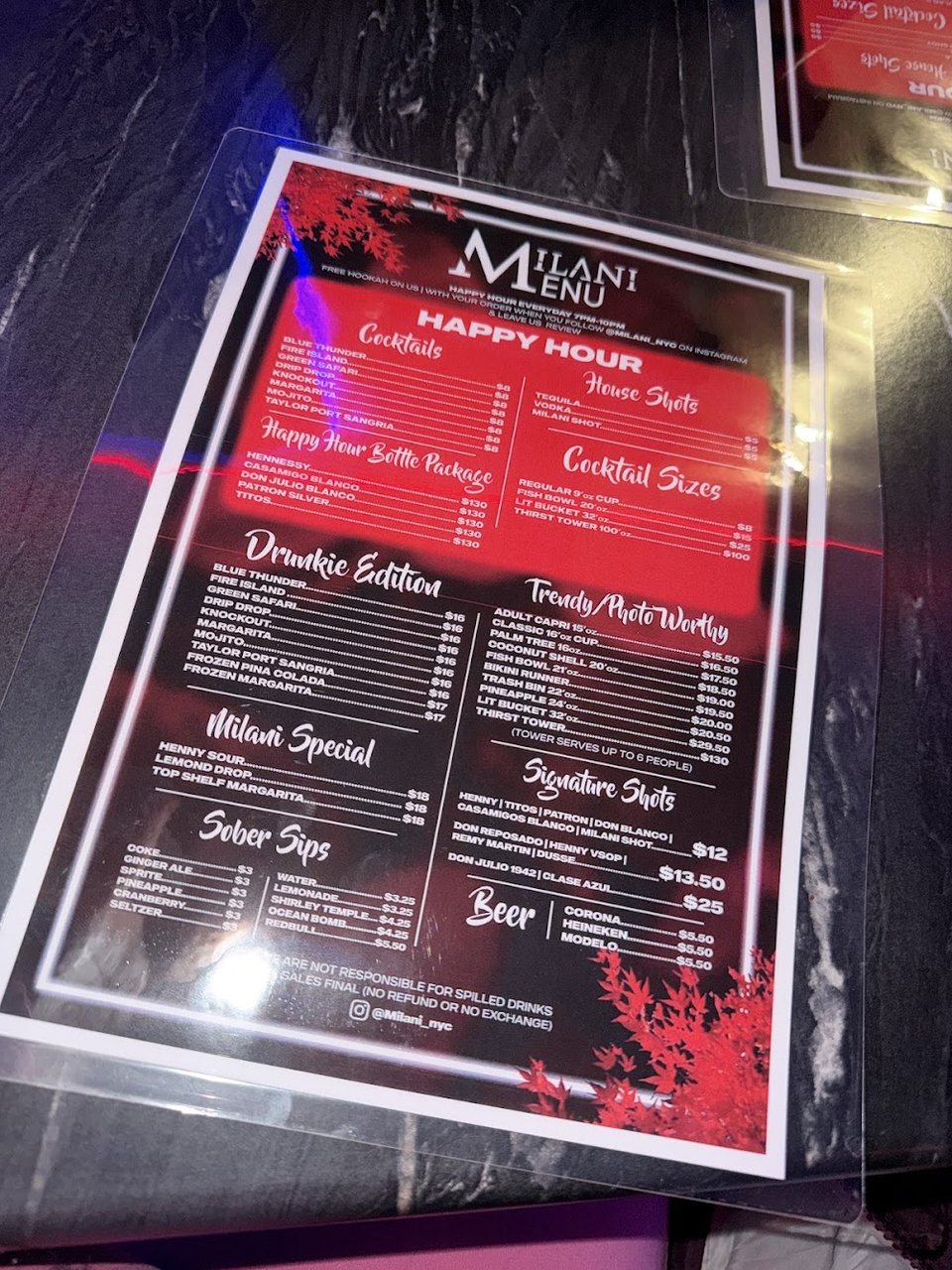 Cocktail menu beside a dimly lit table.
